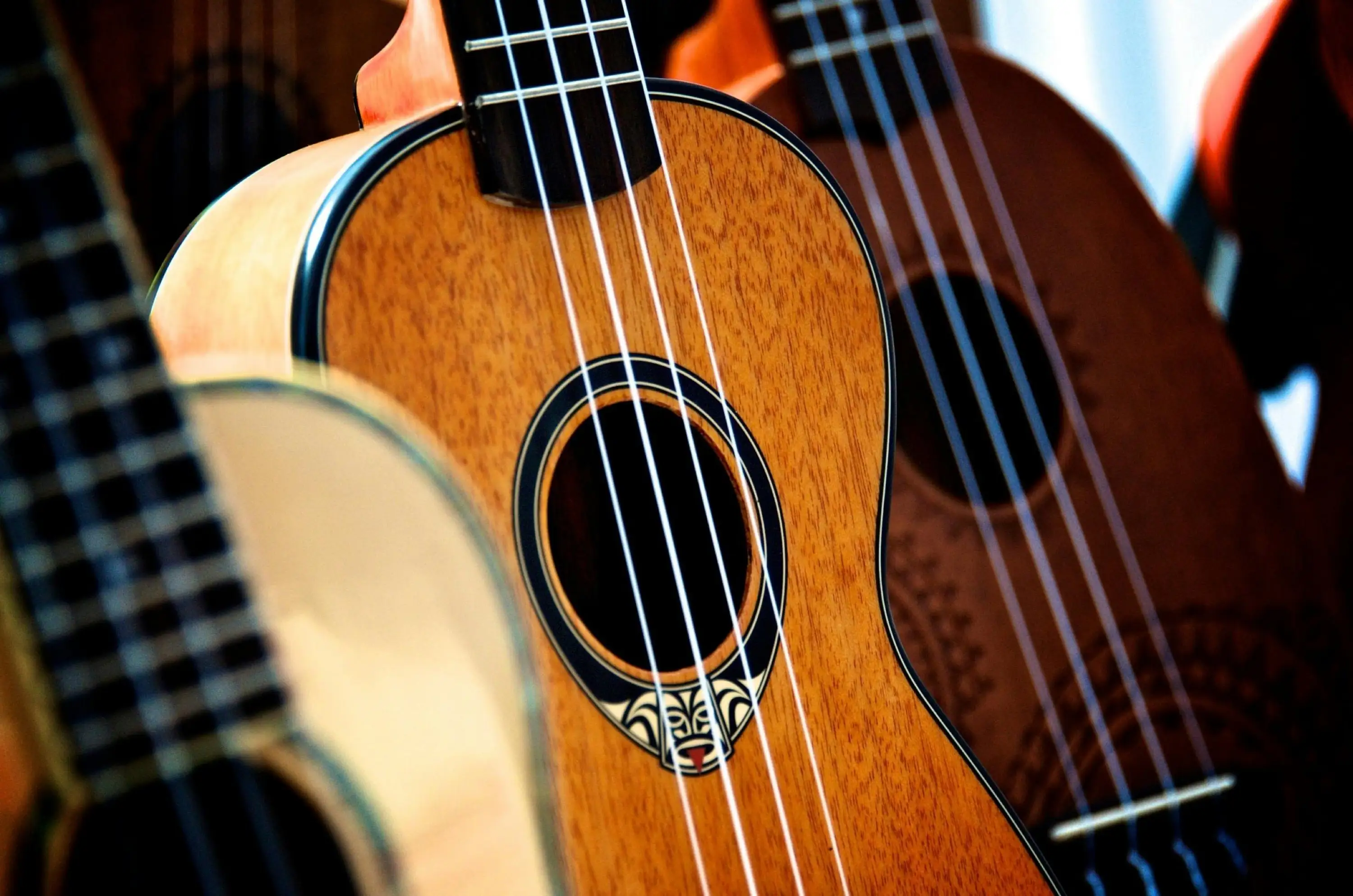 A close-up view of several ukuleles showcasing their intricate wood grain and decorative sound holes, highlighting their craftsmanship.