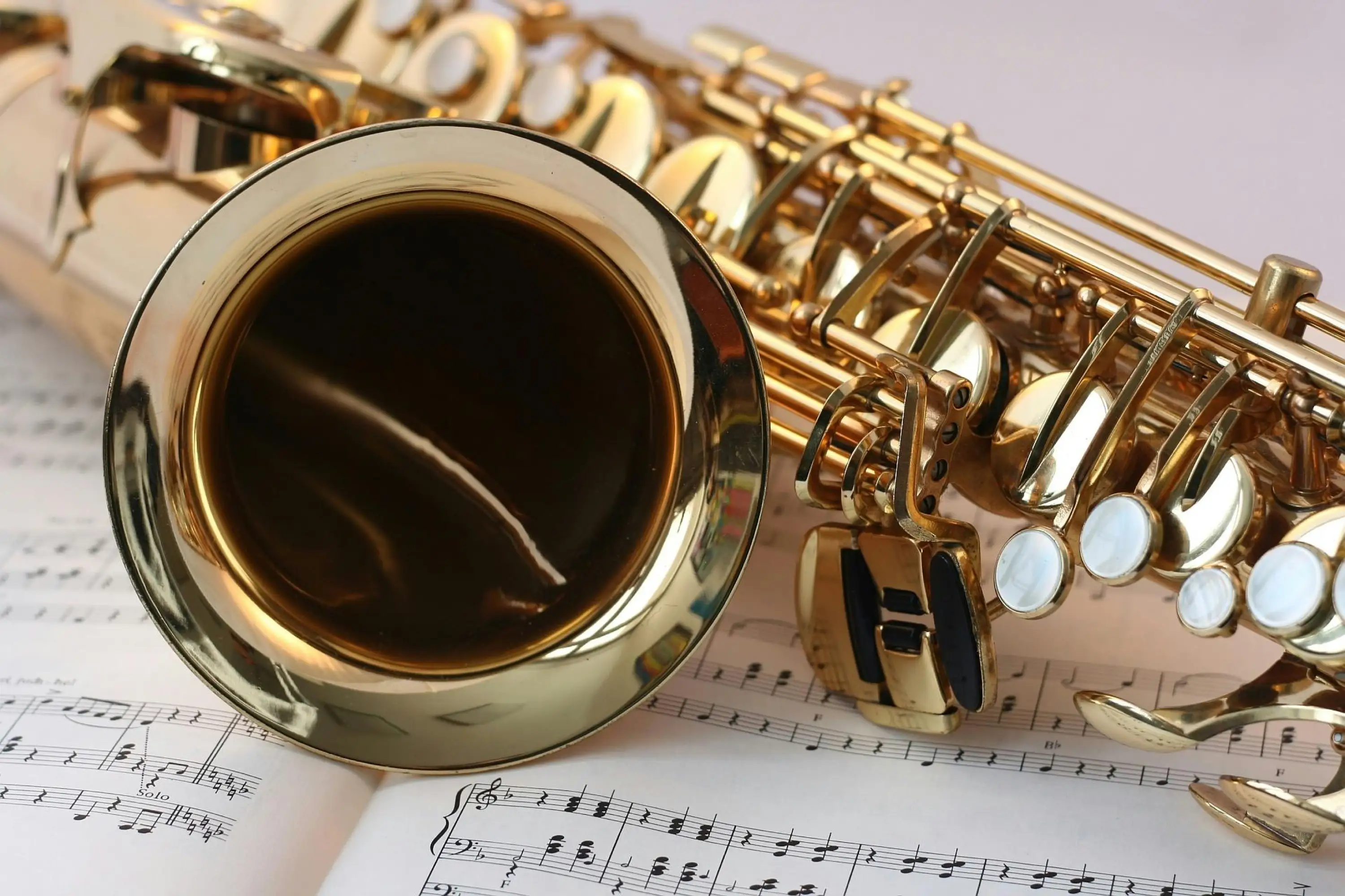 A golden saxophone rests atop an open sheet of musical notation, symbolizing music and artistry.
